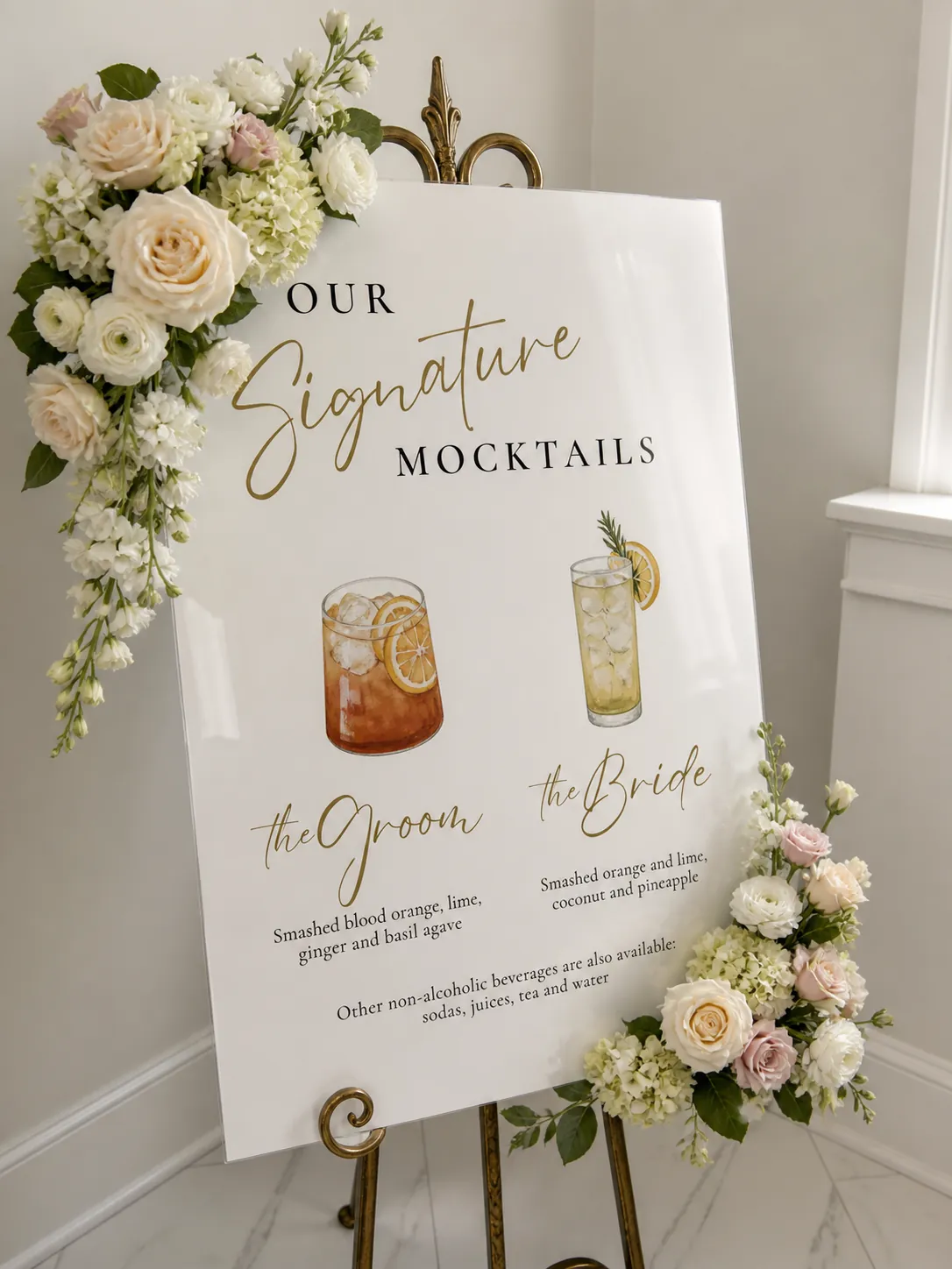 Signature mocktails sign on a gold easel, framed with cream and blush florals
